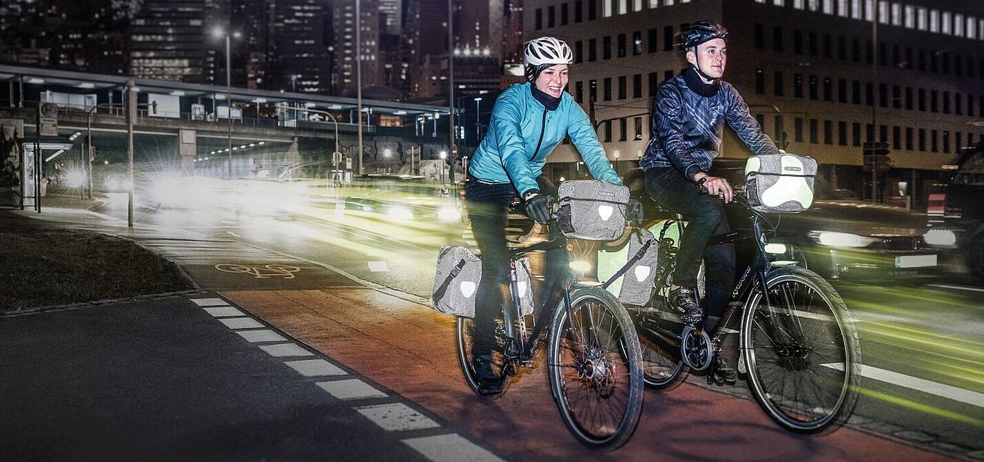 Radfahren bei Dunkelheit Eine Frau und ein Mann fahren bei Dunkelheit in der Stadt mit dem Rad.
